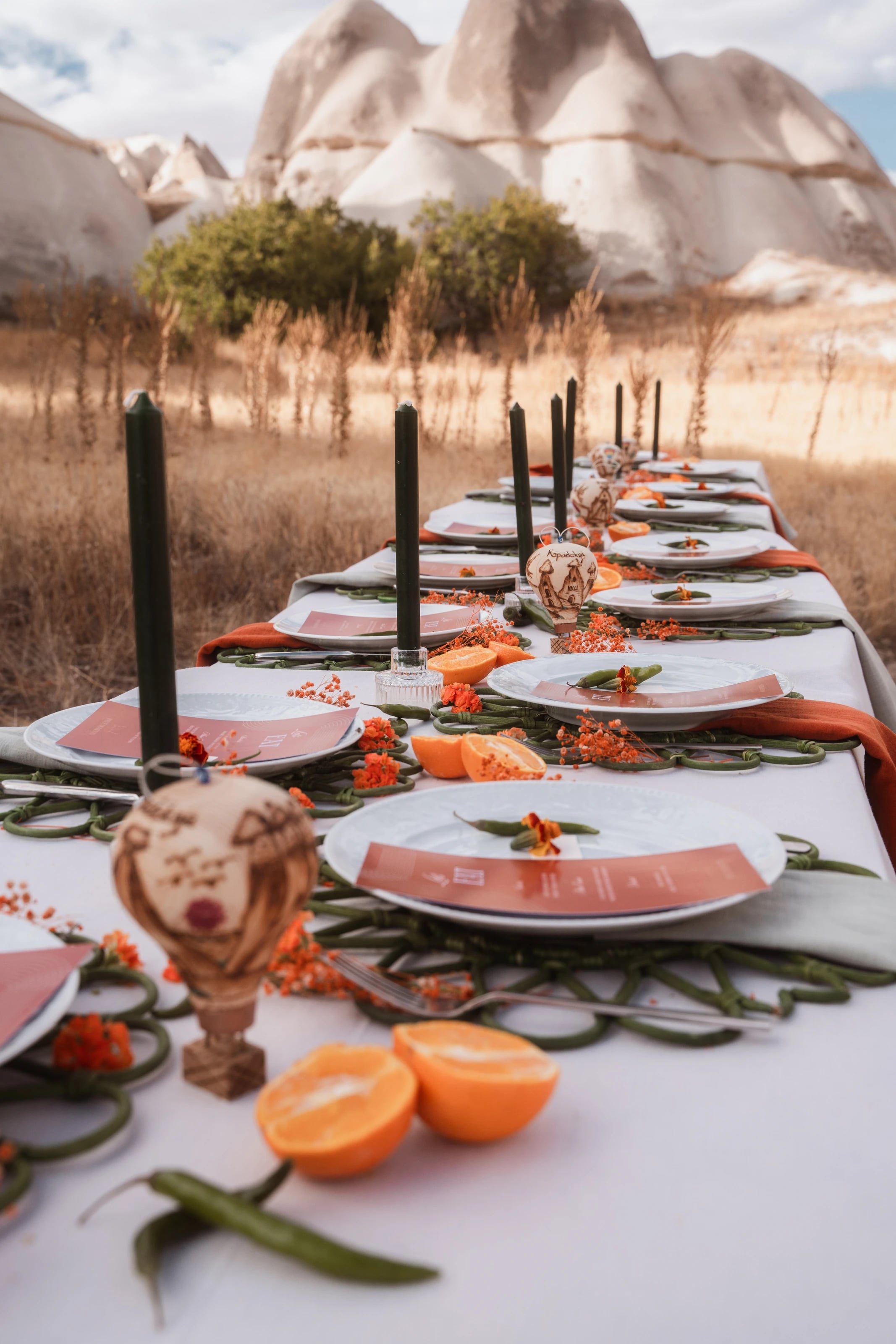 Lange gedeckte Tafel mit orangefarbenen Akzenten vor den Felsformationen Kappadokiens.