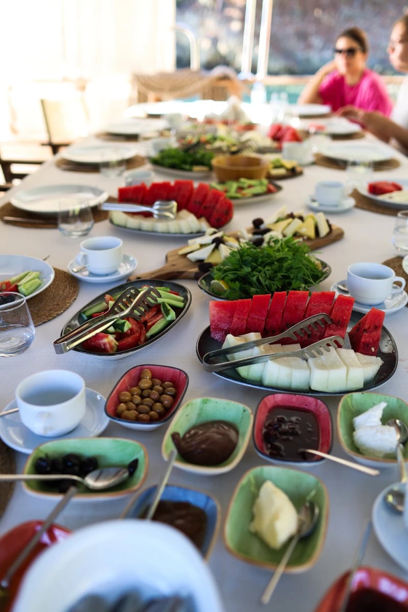 Reich gedeckter Frühstückstisch an Bord mit Wassermelone, Käse, Oliven, Aufstrichen und frischen Kräutern